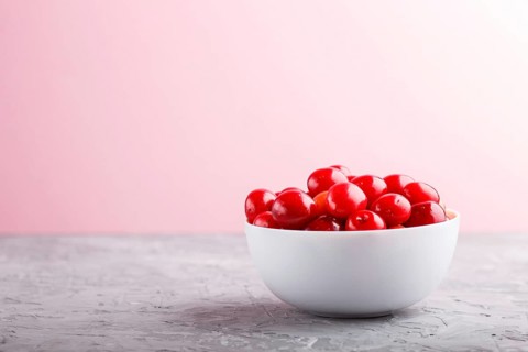 Fresh red sweet cherry in white bowl on gray and pink background. side view, close up, selective