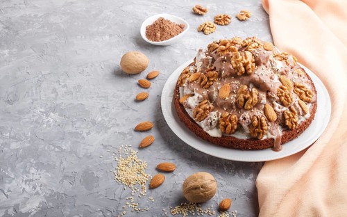 Homemade cake with milk cream, cocoa, almond, hazelnut on a gray concrete background with orange