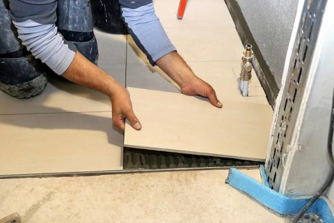 Tiler lays modern large floor tiles in a bathroom
