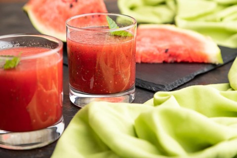 Watermelon juice with chia seeds and mint in glass on a black concrete background with green