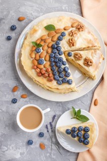 Homemade layered Napoleon cake with milk cream. Decorated with blueberry, almonds, walnuts,
