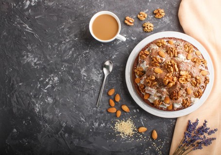 Homemade cake with milk cream, cocoa, almond, hazelnut on a black concrete background with orange