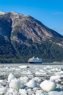 Cruise ship Stella Australis anchored between ice floes in Pia Bay in front of the Pia Glacier,
