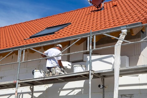 Construction workers insulate a house facade