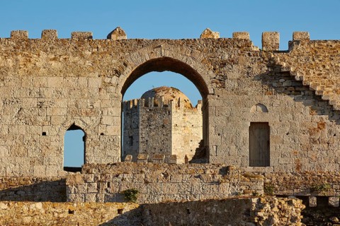 Part of an old castle wall with arches and window openings under a clear blue sky, sea fortress