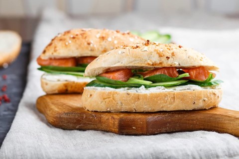 Smoked salmon sandwiches with cucumber and spinach on wooden board on a linen background. side