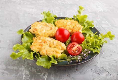 Minced chicken cutlets with lettuce, tomatoes and herbs on a gray concrete background. side view,