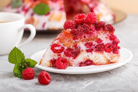Homemade jelly cake with milk, cookies and raspberry on a gray concrete background with cup of