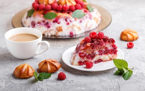 Homemade jelly cake with milk, cookies and raspberry on a gray concrete background with cup of