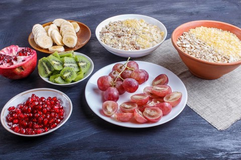 A set of plates with muesli, grapes, kiwi, pomegranate, banana on a black wooden background. close