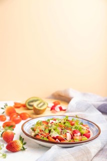 Vegetarian fruits and vegetables salad of strawberry, kiwi, tomatoes, microgreen sprouts on white