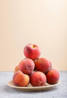 Fresh peaches on a plate on gray and orange pastel background. side view, close up
