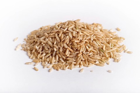 Pile of brown rice isolated on white background. Closeup
