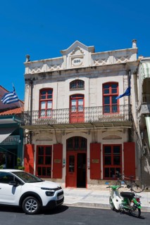 Historic neoclassical building with striking red windows and parked scooter, Museum of Silk Art,