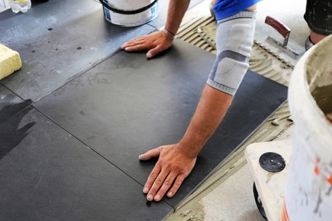 Tiler lays modern large floor tiles in a bathroom