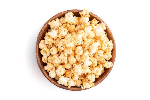Popcorn with caramel in wooden bowl isolated on white background. Top view, flat lay, close up