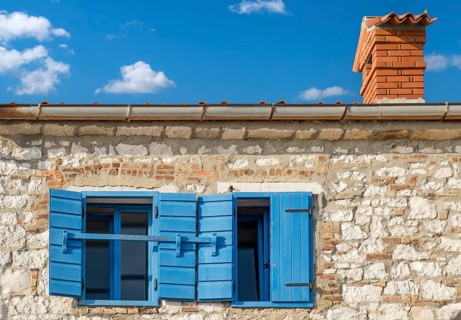 A rustic building with blue shutters under a clear blue sky with few clouds, Istria, Croatia,