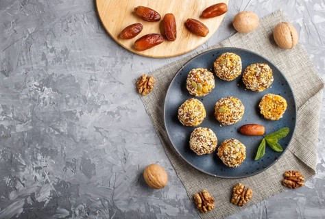 Energy ball cakes with dried apricots, sesame, linen, walnuts and dates with green mint leaves on a