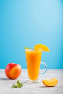 Glass of peach juice on a gray and blue background. Morninig, spring, healthy drink concept. Side