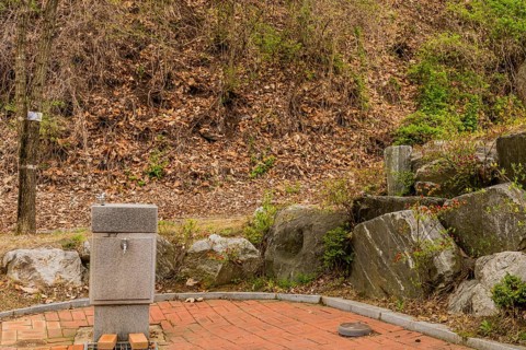 Water fountain in public park next to stack of large boulders in South Korea