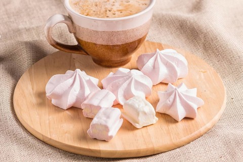 Sweet buns, meringues and coffee cup on a wooden board and linen tablecloth