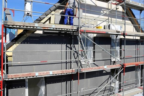 Construction workers insulate a house facade