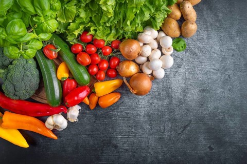 Fresh lettuce, courgettes, broccoli, tomatoes, peppers, mushrooms, onions and potatoes arranged on