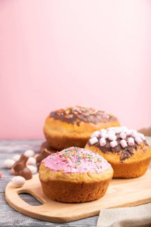 Homemade glazed and decorated easter pies with chocolate eggs and rabbits on a gray and pink