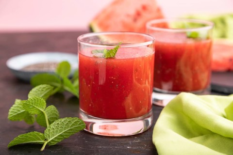 Watermelon juice with chia seeds and mint in glass on a black concrete background with green
