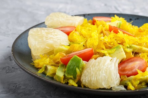 Fried pomelo with tomatoes and avocado on gray concrete background. side view, close up, myanmar