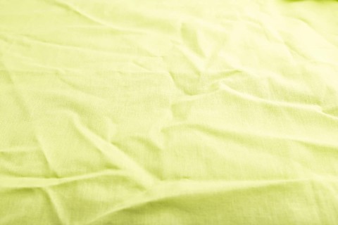 Fragment of smooth green linen tissue. Side view, natural textile background and texture