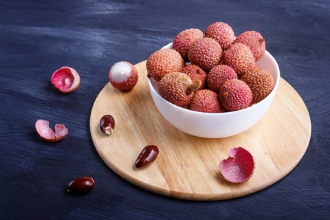 Lychee in a white plate on a black wooden background, close up