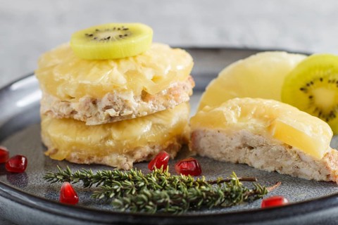 Pieces of baked pork with pineapple, cheese and kiwi on gray plate, side view, close up, selective