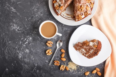 Homemade cake with milk cream, cocoa, almond, hazelnut on a black concrete background with orange