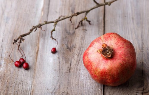 Ripe garnet with a branch on a rustic wooden background