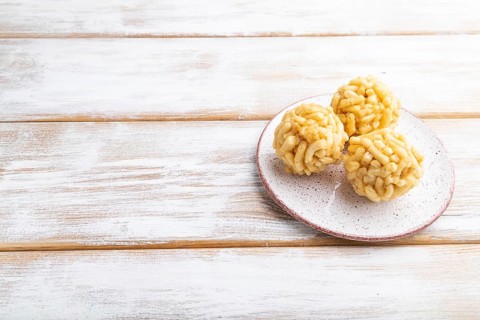 Traditional Tatar candy chak-chak made of dough and honey on a white wooden background. Side view,