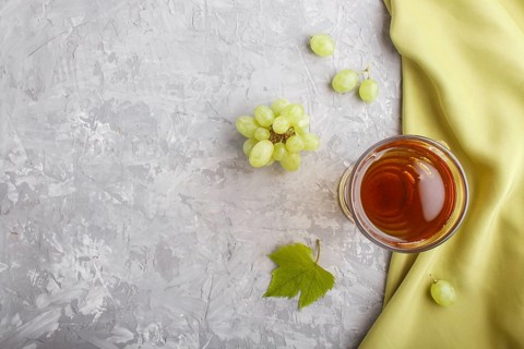 Glass of green grape juice with green textile on a gray concrete background. Morninig, spring,