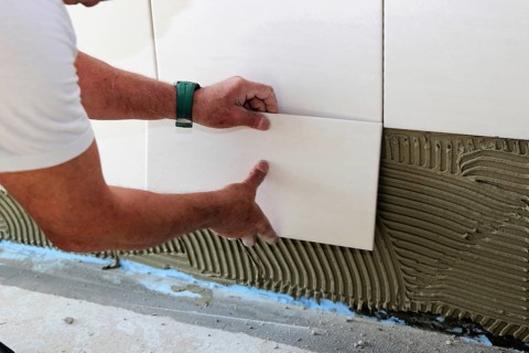 Tiler lays modern wall tiles
