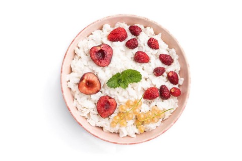 Rice flakes porridge with milk and strawberry in ceramic bowl isolated on white background. Top