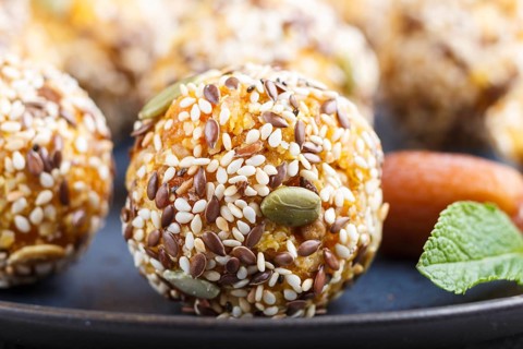 Energy ball cakes with dried apricots, sesame, linen, walnuts and dates with green mint leaves on a