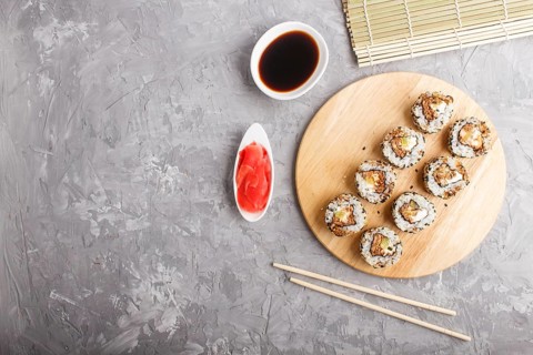 Japanese maki sushi rolls with salmon, sesame, cucumber chopsticks, soy sauce and marinated ginger