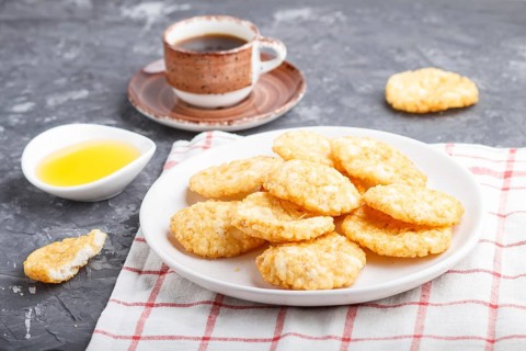 Traditional japanese rice chips cookies with honey and soy sauce on a white ceramic plate and a cup
