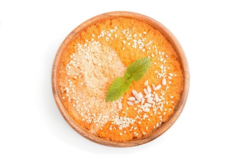 Carrot cream soup with sesame seeds in wooden bowl isolated on white background. top view, flat