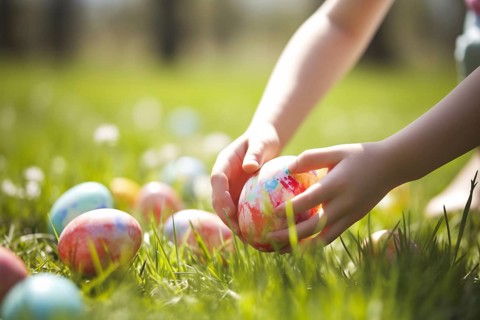 CHild picking up colorful Easter egg from grass during egg hunt. KI generiert, generiert AI