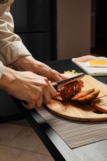 Close up side view of hands of unrecognizable woman cutting tomato for sandwich