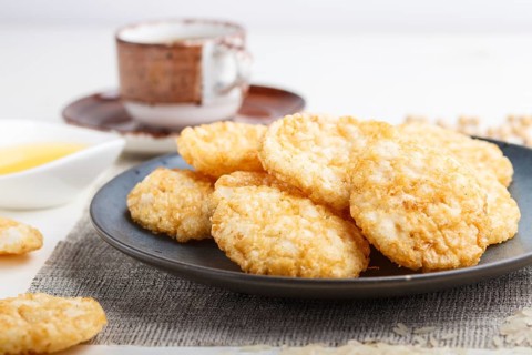 Traditional japanese rice chips cookies with honey and soy sauce on a blue ceramic plate and a cup