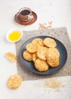 Traditional japanese rice chips cookies with honey and soy sauce on a blue ceramic plate and a cup