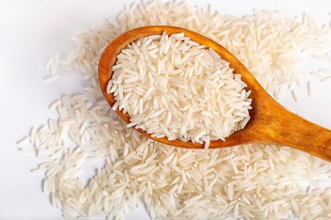 Pile of basmati rice in a wooden spoon isolated on white background