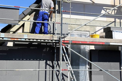 Construction workers insulate a house facade
