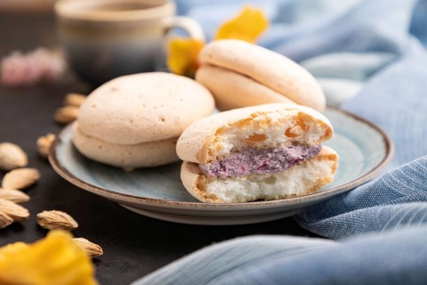 Meringues cakes with cup of coffee on a black concrete background and blue linen textile. Side